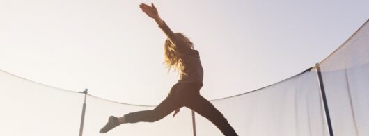 active little girl jumping trampoline against sky e1633897364276